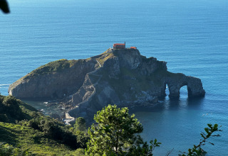 Blick auf eine berühmte Felseninsel mit Stufenweg und Haus auf der Spitze bei Wecamp Cudillero, Asturien, Spanien.