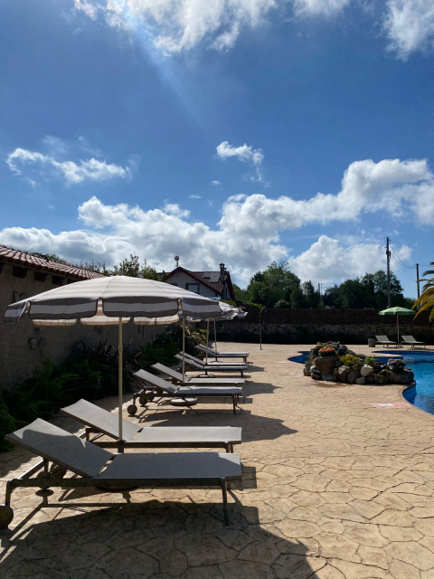 Sonnenliegen mit Schirmen an einem sonnigen Pool im Wecamp Cudillero Ferienpark in Asturien, Spanien.
