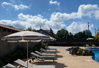 Sonnenliegen mit Schirmen an einem sonnigen Pool im Wecamp Cudillero Ferienpark in Asturien, Spanien.