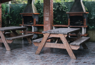 Überdachter Grillbereich mit Holzbänken und gemauerten Grills im Ferienpark Wecamp Cudillero, Asturien.
