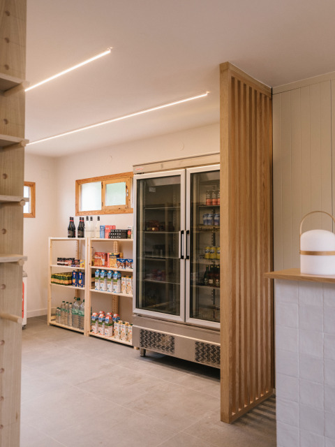 Moderner Laden im Wecamp Cudillero, Asturien, Spanien mit Holzregalen und einem großen Kühlschrank.