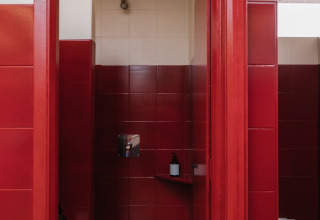 Modernes Gemeinschaftsbad mit roten Fliesen, Dusche und WC im Wecamp Cudillero, Asturias, Spanien.
