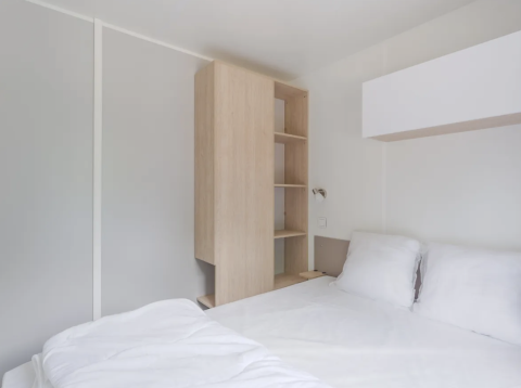 Bright modern bedroom with a double bed and wood closet at Cottage, Campsite Seasonova du Chêne in France.