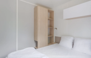 Bright modern bedroom with a double bed and wood closet at Cottage, Campsite Seasonova du Chêne in France.