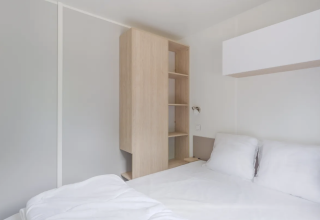 Bright modern bedroom with a double bed and wood closet at Cottage, Campsite Seasonova du Chêne in France.