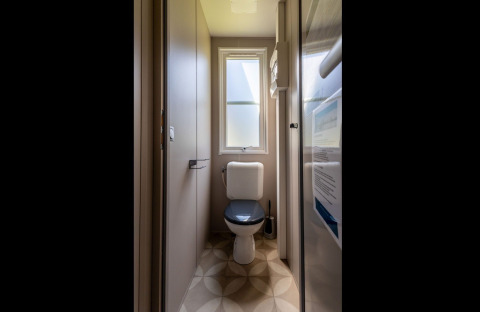 Narrow bathroom with toilet and window, photographed in Lodge «XL - comfort» at Holiday Park Bergumermeer, Netherlands.