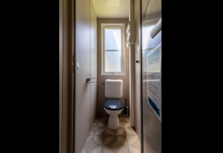 Narrow bathroom with toilet and window, photographed in Lodge «XL - comfort» at Holiday Park Bergumermeer, Netherlands.