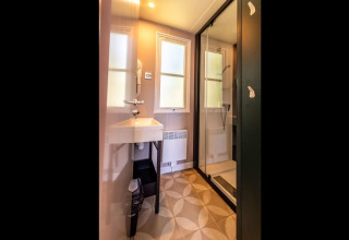 Modern bathroom with glass shower, sink, and windows at Lodge «XL - comfort» in Holiday Park Bergumermeer.