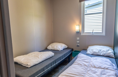 Modern room with two single beds, window, and wall lamp in Lodge «XL - comfort» in the Netherlands.