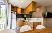 Modern kitchen setup with wooden furniture, appliances and dining area in Lodge «XL - comfort» at Holiday Park Bergumermeer.