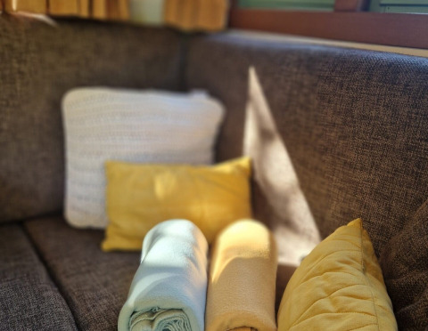 Canapé brun avec coussins et couvertures blancs et jaunes dans la tiny house 'Hans en Grietje' aux Pays-Bas.