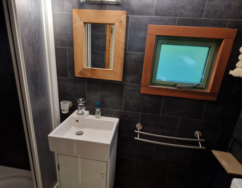 Salle de bains moderne dans la tiny house Hans en Grietje avec lavabo, miroir et fenêtre, Buytenplaets Suydersee.