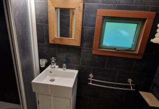 Salle de bains moderne dans la tiny house Hans en Grietje avec lavabo, miroir et fenêtre, Buytenplaets Suydersee.