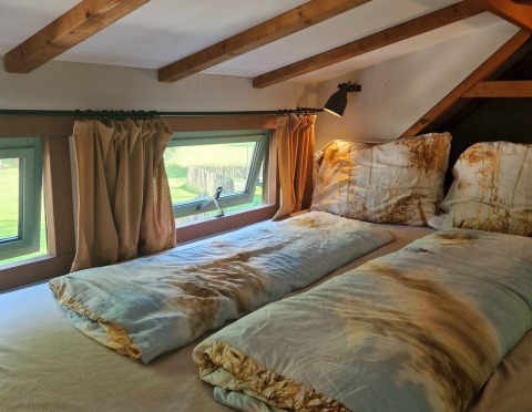 Coin nuit du tiny house Hans en Grietje, avec poutres en bois et fenêtres, Buytenplaets Suydersee.