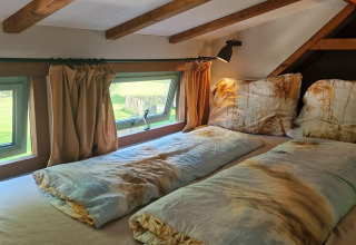 Coin nuit du tiny house Hans en Grietje, avec poutres en bois et fenêtres, Buytenplaets Suydersee.