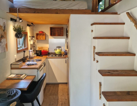 Intérieur de tiny house avec cuisine, mezzanine, escalier en bois et agencement malin aux Pays-Bas.