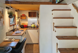 Intérieur de tiny house avec cuisine, mezzanine, escalier en bois et agencement malin aux Pays-Bas.