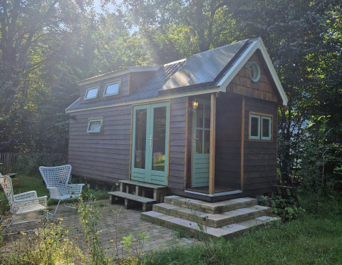 Tiny house «Hans en Grietje» à Buytenplaets Suydersee aux Pays-Bas, entourée de verdure et d’arbres.