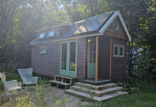 Tiny house «Hans en Grietje» à Buytenplaets Suydersee aux Pays-Bas, entourée de verdure et d’arbres.