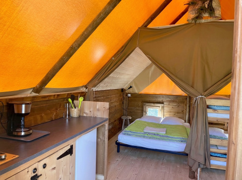 Binnenkant van safaritent Glamp tent «2.0» bij Weekend Glamping Resort in Italië, met bedden en kitchenette.