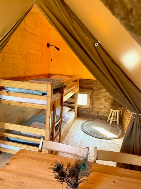 Binnenzicht van Glamp tent 2.0 bij Weekend Glamping Resort in Italië met houten stapelbedden en meubels.