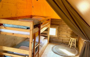 Interior view of Glamp tent 2.0 at Weekend Glamping Resort in Italy, featuring wooden bunk beds and decor.