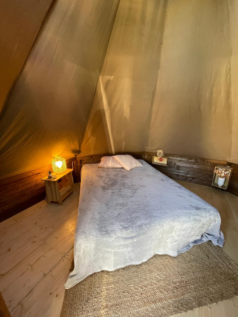 Interieur van Tipi Junior tipi tent bij Weekend Glamping Resort in Italië met bed en warme verlichting.