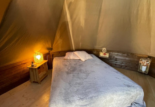 Interieur van Tipi Junior tipi tent bij Weekend Glamping Resort in Italië met bed en warme verlichting.