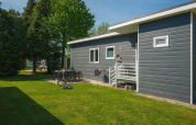 Group Yard Chalets at De Scherpenhof, Netherlands, with people relaxing outside on a sunny green lawn.
