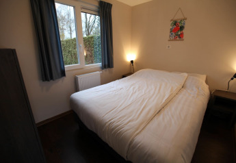 Cozy bedroom at Group Yard Chalets in De Scherpenhof, Netherlands with double bed and window view.