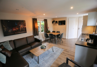 Moderne stue og køkken i Group Yard Chalets på De Scherpenhof, Holland, med spise- og sofaområde.