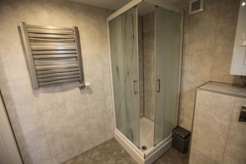 Modern bathroom with glass shower, towel warmer, and trash bin at Group Yard Chalets, De Scherpenhof, NL