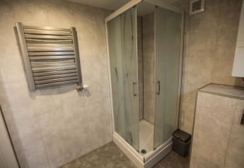Modern bathroom with glass shower, towel warmer, and trash bin at Group Yard Chalets, De Scherpenhof, NL