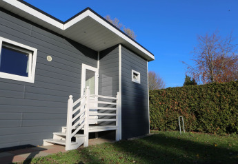 Entrance of a modern lodge at Group Yard Chalets, De Scherpenhof, Netherlands, with white railings and hedges.