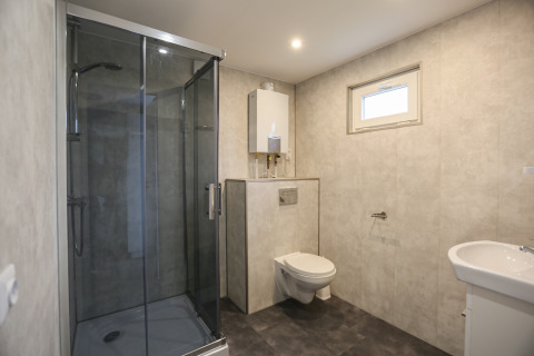 Modern bathroom with glass shower, wall-mounted toilet, and sink at Group Yard Chalets in the Netherlands.