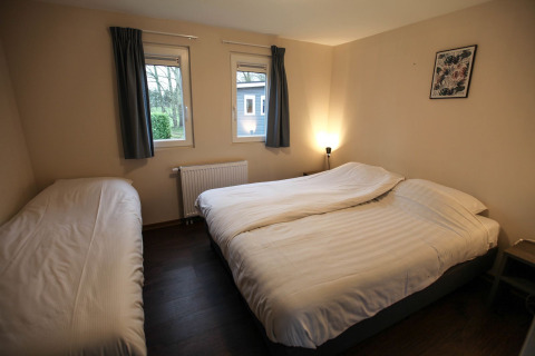 Et hyggeligt soveværelse på Group Yard Chalets i De Scherpenhof, Holland, med dobbeltseng og enkeltseng.