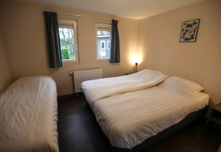 Cozy bedroom at Group Yard Chalets in De Scherpenhof, Netherlands, featuring a double bed and a single bed.