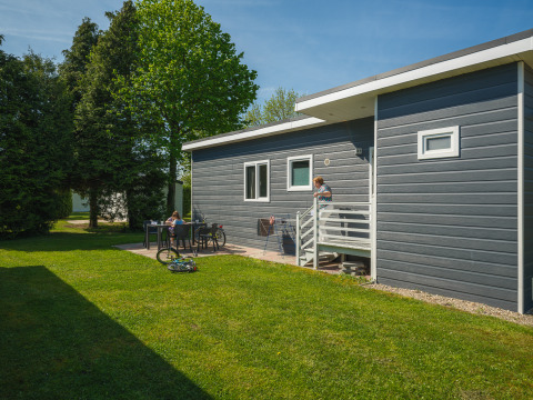 Modern Group Yard Chalet at De Scherpenhof in the Netherlands, with garden, bikes, and people relaxing outside.