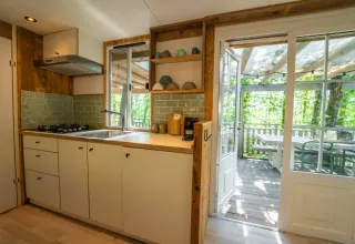 Gezellige keuken in de Bohemian Lodge bij Chianti Glamping Resort met uitzicht op een houten terras tussen bomen.