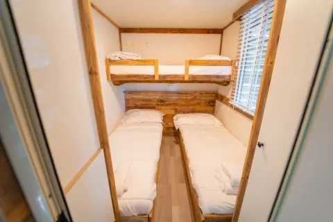 Gezellige kamer met een stapelbed en twee eenpersoonsbedden in Bohemian Lodge, Chianti Glamping Resort, Italië.