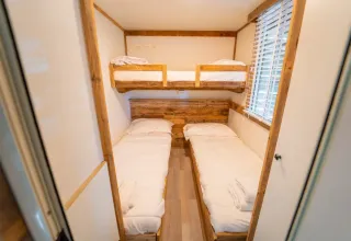 Gezellige kamer met een stapelbed en twee eenpersoonsbedden in Bohemian Lodge, Chianti Glamping Resort, Italië.