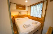 Gemütliches Schlafzimmer mit Holzakzenten im Bohemian Lodge, Chianti Glamping Resort, Italien, mit Doppelbett.