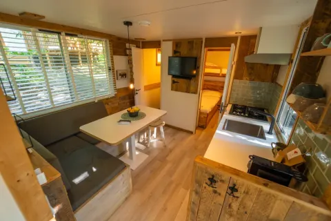 Interieur van de Bohemian Lodge bij Chianti Glamping Resort in Italië met eethoek, keuken en slaapkamer.