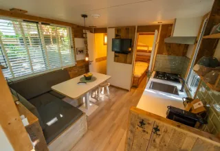 Interieur van de Bohemian Lodge bij Chianti Glamping Resort in Italië met eethoek, keuken en slaapkamer.