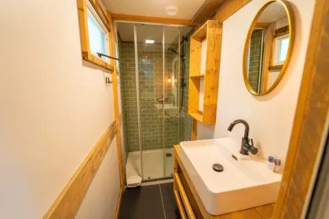 Moderne badkamer met glazen douche, houten accenten en spiegel in Bohemian Lodge, Chianti Glamping Resort, Italië.