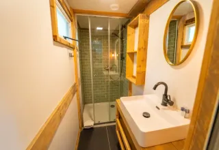 Moderne badkamer met glazen douche, houten accenten en spiegel in Bohemian Lodge, Chianti Glamping Resort, Italië.