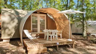 Safari-Zelt namens Coco Suite mit Terrasse, Tisch, Stühlen und Sonnenschirm im bewaldeten Gebiet.