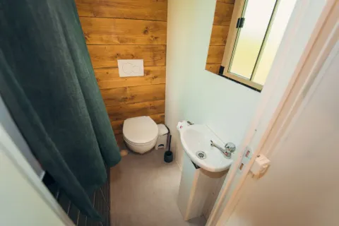 Petite salle de bain avec toilettes, lavabo et rideau de douche à Cottage Classic, Chianti Glamping Resort, Italie.