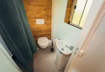 Baño pequeño con inodoro, lavabo y cortina en Cottage Classic, Chianti Glamping Resort, Italia.