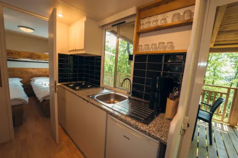 Coin cuisine avec évier, plaques de cuisson et verrerie, menant à la chambre et la terrasse, Cottage Classic, Chianti Glamping Resort.